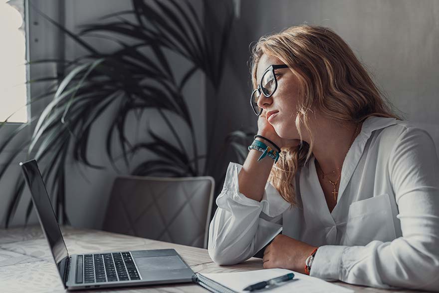 Nachdenkliche Frau vor Laptop - Tinnitus und Gesundheitsvorsorge